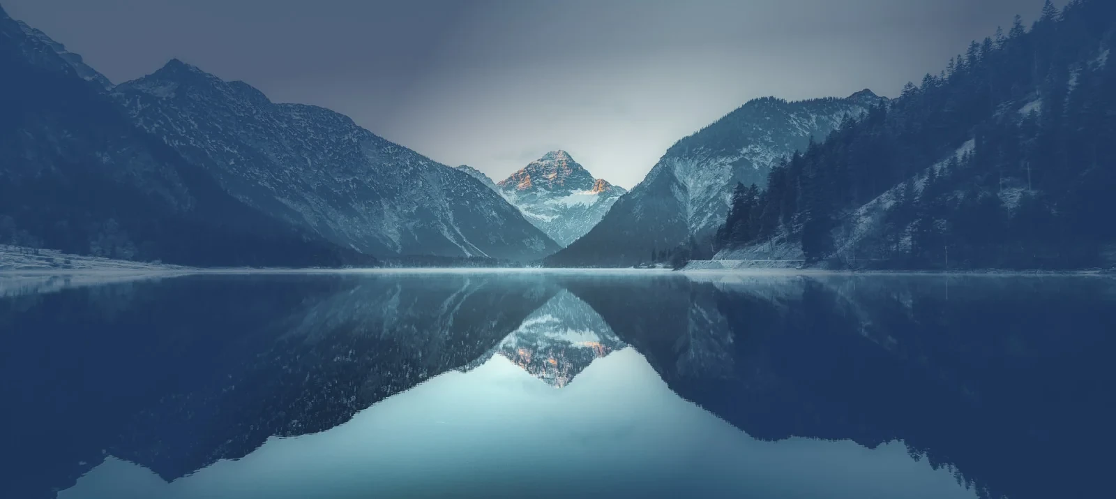 Berg, der sich in einem See spiegelt, symbolisiert die Präzision unserer akustischen Lösungen. / Mountain reflecting in a lake, symbolizing the precision of our acoustic solutions.